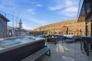 View of patio / terrace featuring a mountain view, a hot tub, and an outdoor living space with a fire pit