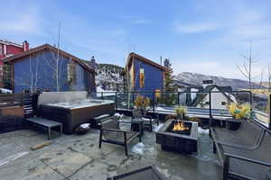 View of patio featuring a mountain view, a hot tub, and an outdoor fire pit