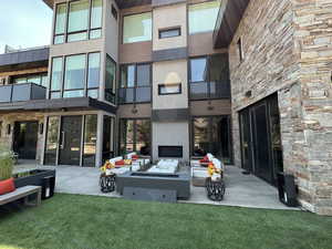 Rear view of property featuring an outdoor hangout area, a patio area, a balcony, and a yard