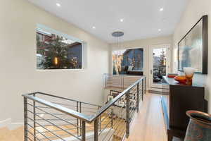 Hallway with an upstairs landing, light wood-style flooring, and recessed lighting