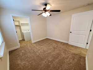 Unfurnished bedroom with a walk in closet, light colored carpet, and ceiling fan