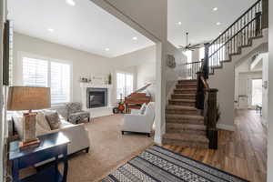 Living area with a glass covered fireplace, stairway, plenty of natural light, light wood-style floors, and recessed lighting