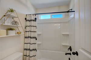 Full bath featuring toilet and shower / bath combo with shower curtain