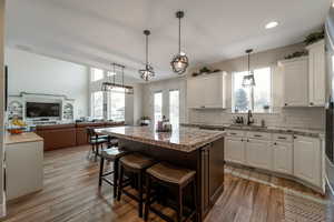 Kitchen featuring pendant lighting, a kitchen breakfast bar, white cabinets, a kitchen island, and recessed lighting