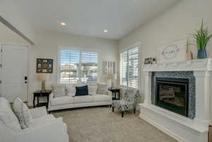 Living room featuring healthy amount of natural light, a tiled fireplace, carpet flooring, and recessed lighting