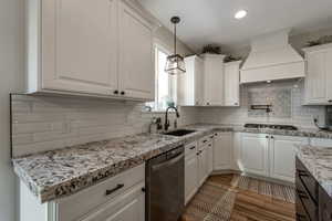 Kitchen with white cabinetry, pendant lighting, premium range hood, stainless steel appliances, and light stone countertops