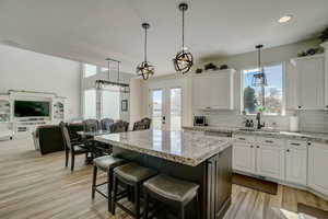 Kitchen with white cabinets, open floor plan, a kitchen bar, pendant lighting, and a kitchen island