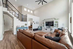 Living room with a towering ceiling, wood finished floors, ceiling fan, and recessed lighting