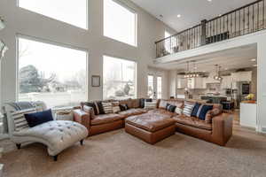 Living area with recessed lighting, a high ceiling, and light colored carpet