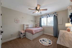 Carpeted bedroom with baseboards and a ceiling fan