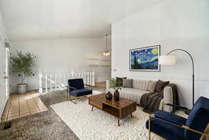 Living room featuring light colored carpet, vaulted ceiling, ceiling fan, and light tile patterned floors