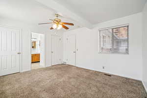Unfurnished bedroom featuring light carpet, a ceiling fan, connected bathroom, multiple closets, and beam ceiling