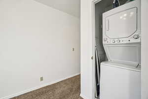 Laundry area with carpet and stacked washer / drying machine