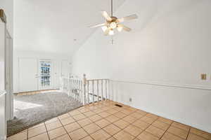 Tiled empty room featuring carpet floors, high vaulted ceiling, and ceiling fan