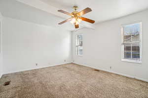 Carpeted empty room featuring beamed ceiling and ceiling fan