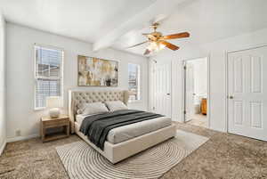 Carpeted bedroom featuring connected bathroom, beam ceiling, and ceiling fan