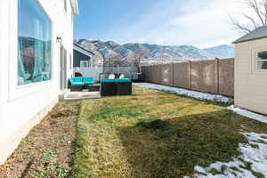 Fenced backyard with an outdoor living space, a patio, a mountain view, and a trampoline