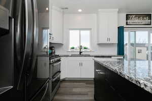 Kitchen featuring dark cabinets, freestanding refrigerator, dark stone countertops, white cabinets, and dark wood-type flooring