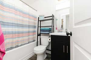 Full bath with vanity, shower / bath combo, and dark wood-type flooring