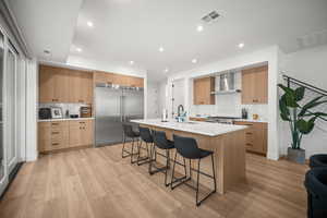 Kitchen with modern cabinets, built in refrigerator, a kitchen bar, decorative backsplash, and an island with sink