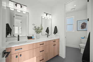 Full bathroom with double vanity, dark tile patterned floors, and recessed lighting