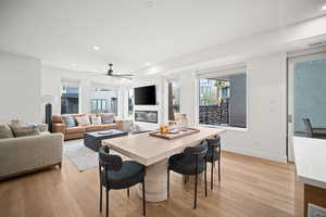 Dining area with light wood-style flooring, a glass covered fireplace, recessed lighting, and ceiling fan