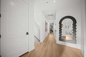 Hall featuring light wood-type flooring, recessed lighting, and an upstairs landing