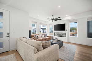 Living room featuring light wood-type flooring, recessed lighting, a glass covered fireplace, and ceiling fan