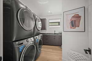 Laundry room featuring light wood-style flooring, recessed lighting, and stacked washer and clothes dryer