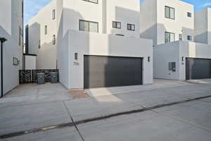 View of property exterior with an attached garage, stucco siding, and driveway