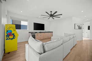 Living room featuring light wood-type flooring, recessed lighting, wine cooler, and a ceiling fan