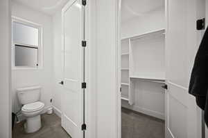 Bathroom featuring a walk in closet and dark tile patterned floors