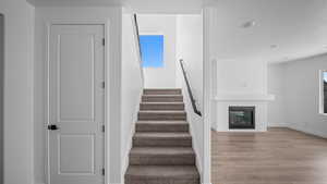 Stairs featuring a fireplace and wood finished floors