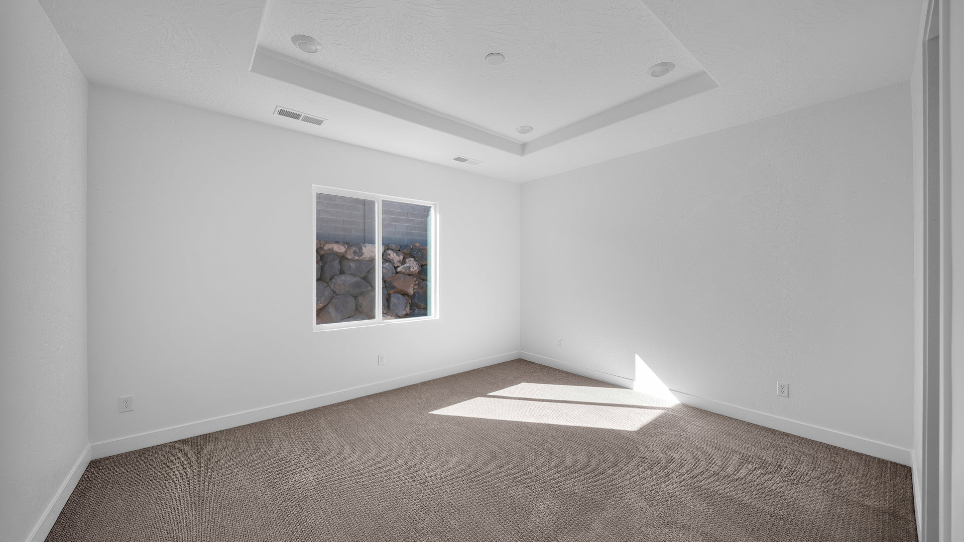 Carpeted spare room featuring a raised ceiling and baseboards