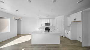 Kitchen with white cabinets, light stone counters, and a center island with sink