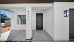 Property entrance featuring a porch and stucco siding