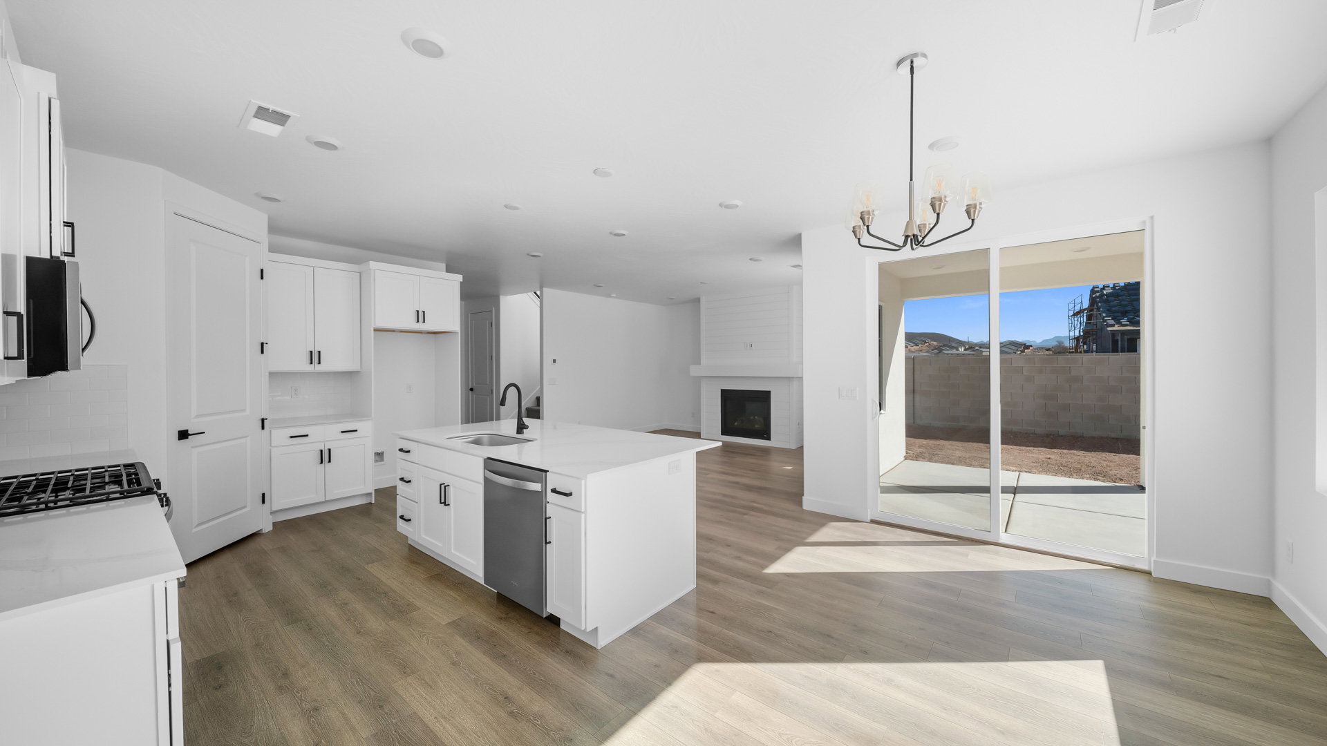 Kitchen featuring a large fireplace, an island with sink, white cabinetry, open floor plan, and light stone countertops
