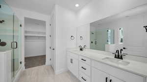 Bathroom with a stall shower, double vanity, and a spacious closet