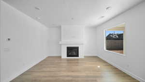 Unfurnished living room featuring light wood-style flooring and a fireplace