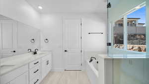 Full bathroom with double vanity, a bath, and recessed lighting