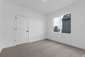 Carpeted spare room featuring baseboards