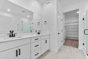 Full bath with a stall shower, a spacious closet, and double vanity
