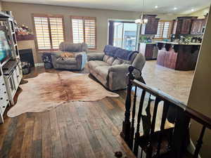 Living room with dark wood-type flooring and suspended lighting