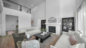 Living area featuring a high ceiling, wood finished floors, a large fireplace, and recessed lighting