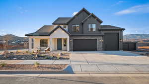 Modern inspired farmhouse with a mountain view, covered porch, board and batten siding, and driveway