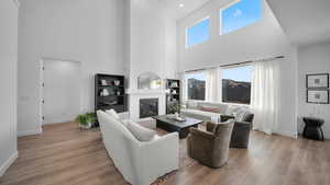 Living area featuring wood finished floors, a high ceiling, and a fireplace