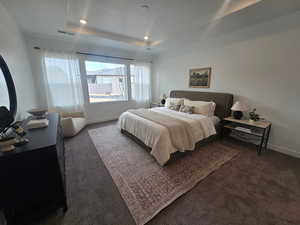 Bedroom with a tray ceiling, dark colored carpet, and recessed lighting