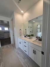 Bathroom featuring a shower stall, double vanity, and wood tiled floors