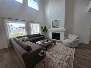 Living room featuring a high ceiling, dark wood-style floors, and a fireplace