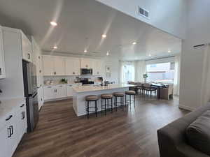 Kitchen featuring a center island with sink, a breakfast bar area, stainless steel appliances, white cabinetry, and recessed lighting